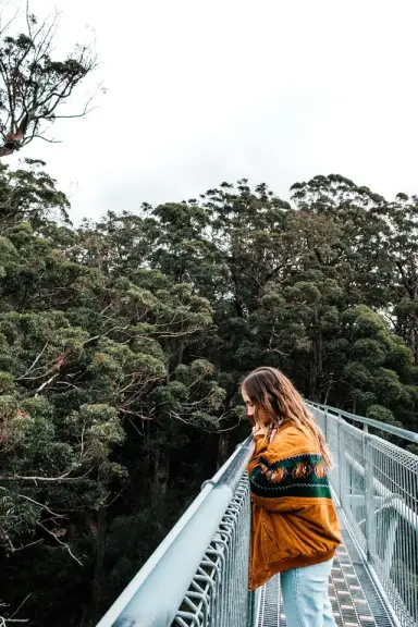 Tourist Admiring Green Trees From Bridge Under White Sky