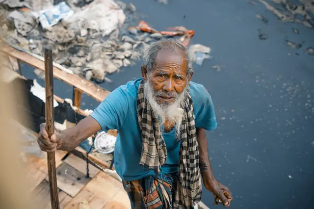 Elderly person near a polluted river. pexels